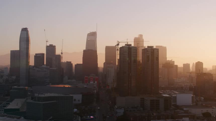 Sun sitting on horizon in red sky glares across city buildings casting them into silhouettes