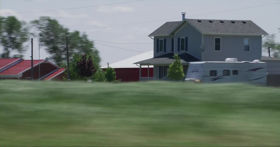 Traveling past a farmhouse and barn with an american flag waving in the breeze