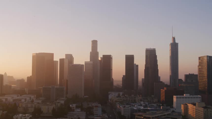 Tall buildings loom over a city in the evening