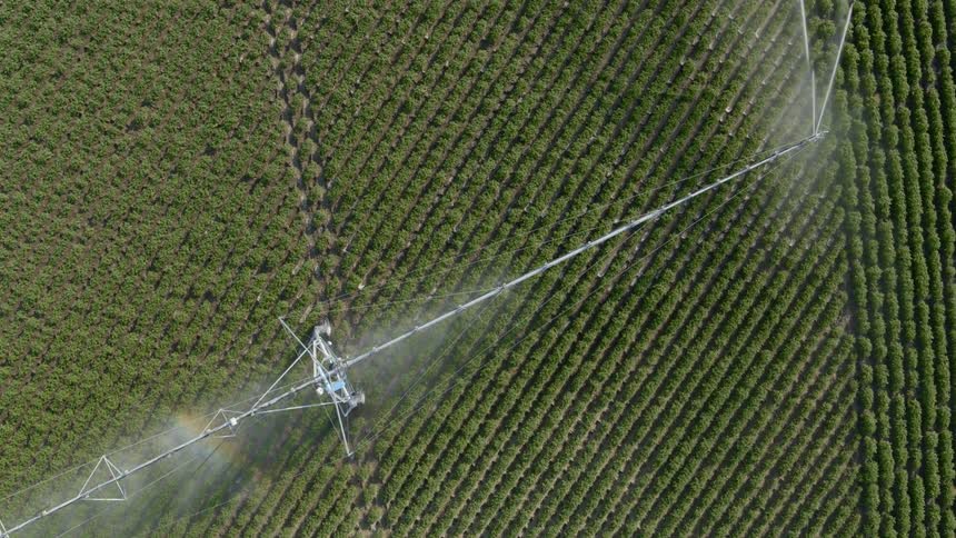 Twisting descent over a sprinkler system spraying water on a large field of crops