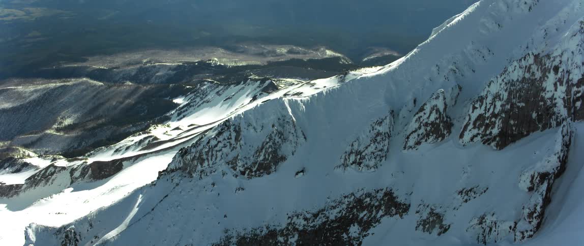 Snow covered mountain towers over green misty valley