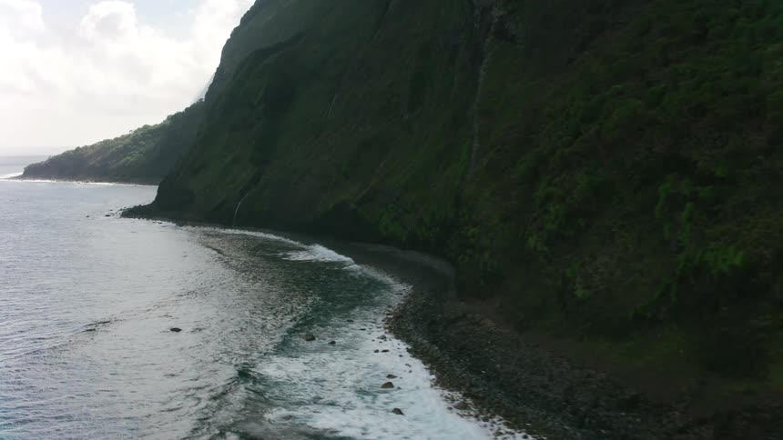Part of shore promontory sits in shadow and part is obscured by mist