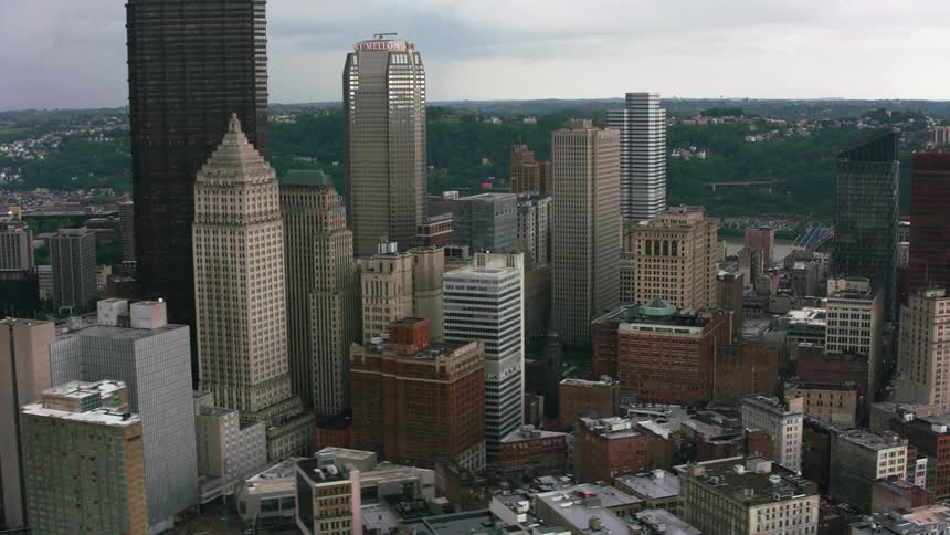 An aerial view of high rise office buildings in a downtown area and vehicles driving on the streets