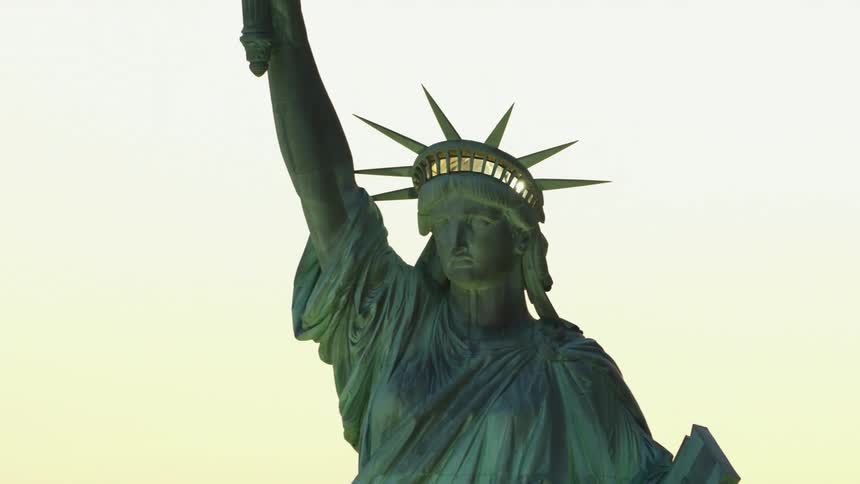 The torch and crown on the statue of liberty is lit up as day turns to night