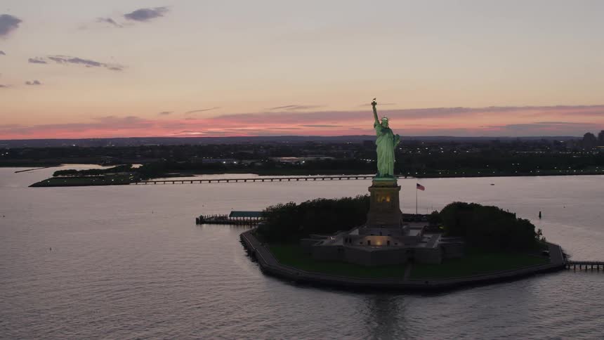 The statue of liberty shines on an island in the sea