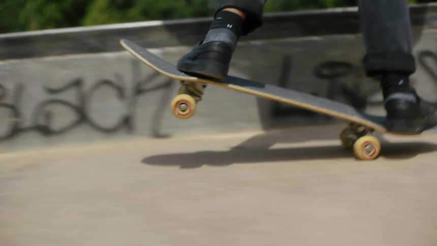 Close up of a person as they skateboard in a park with others skateboarding in the distance