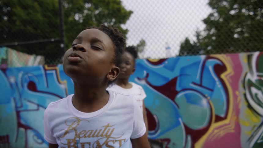 A little girl standing in the playground with eyes closed and lips puckered