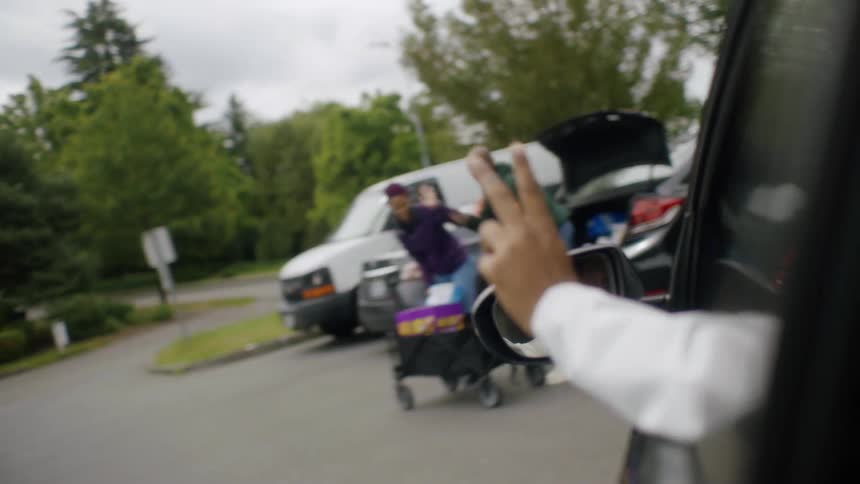 A man waves to people from the car