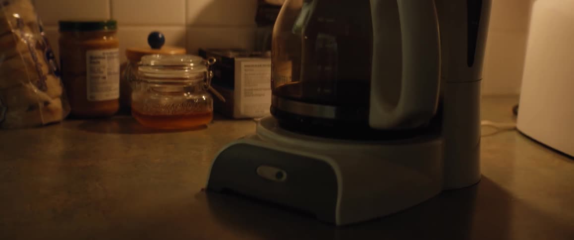 A coffee machine slowly drips coffee into a glass coffee pot on a kitchen counter