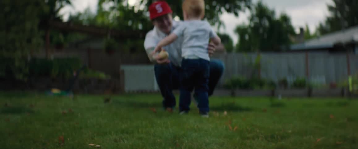 A boy runs into his fathers arms as they fall down laughing
