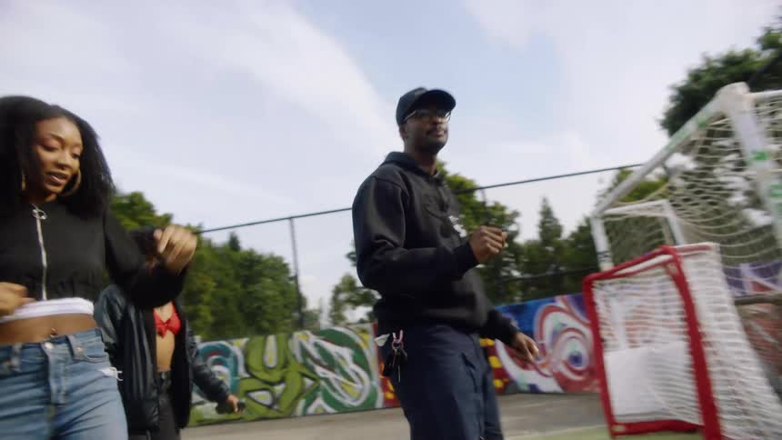 A large group performs a choreographed dance in a park