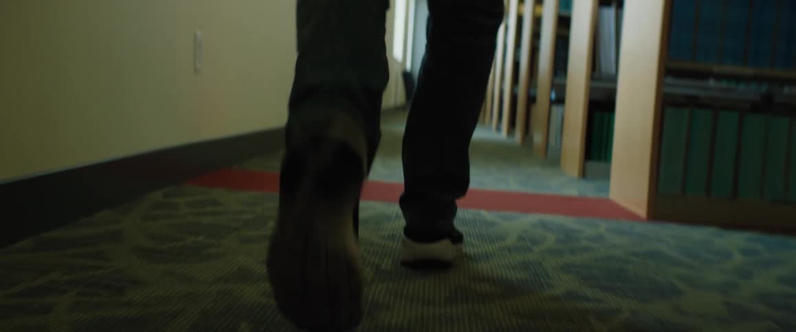 A person is walking through a library during the day time