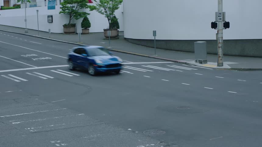 An automobile travels past a building and through an intersection