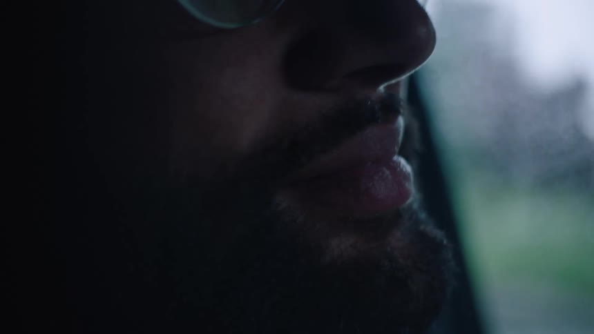 Close up of mans face with beard and glasses driving car