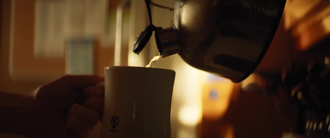 Someone is pouring hot water from a teapot into the cup they are holding