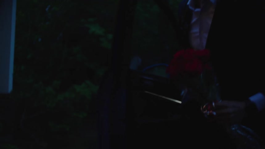 A man exits his car carrying flowers