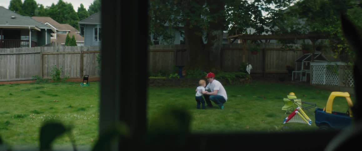 A man runs around with his son and tosses him in the air in their backyard