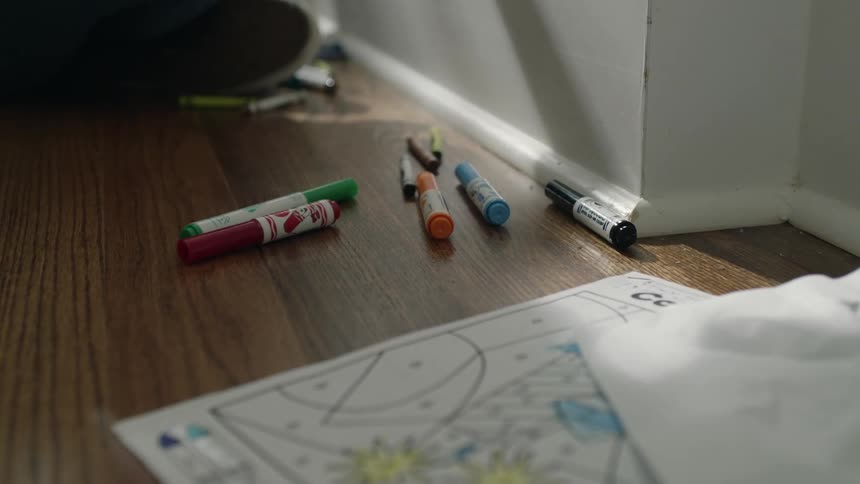 There are crayons and colored markers on the floor with pictures from a coloring book