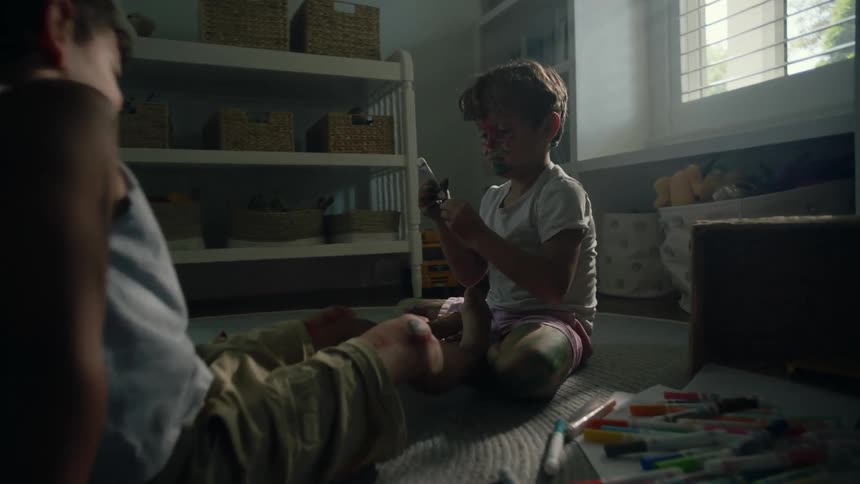 Boys play on floor coloring each other with markers