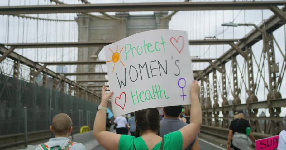 People carry signs as they walk across a bridge during a protest