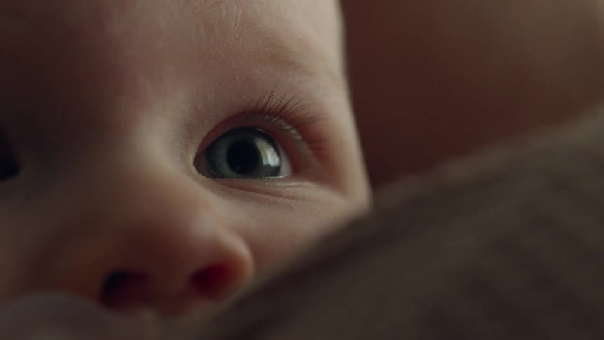 A baby lays its head down on a persons shoulder