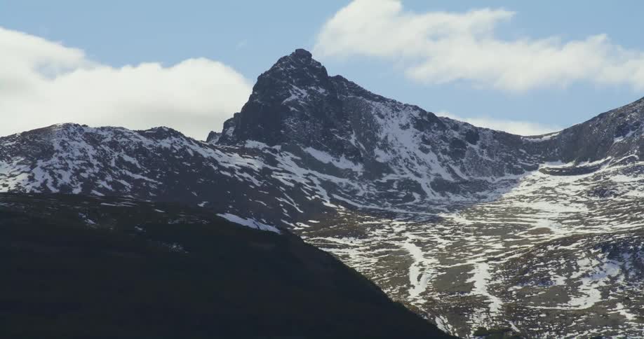 Snow covered mountains with peaks high in a cloudy sky