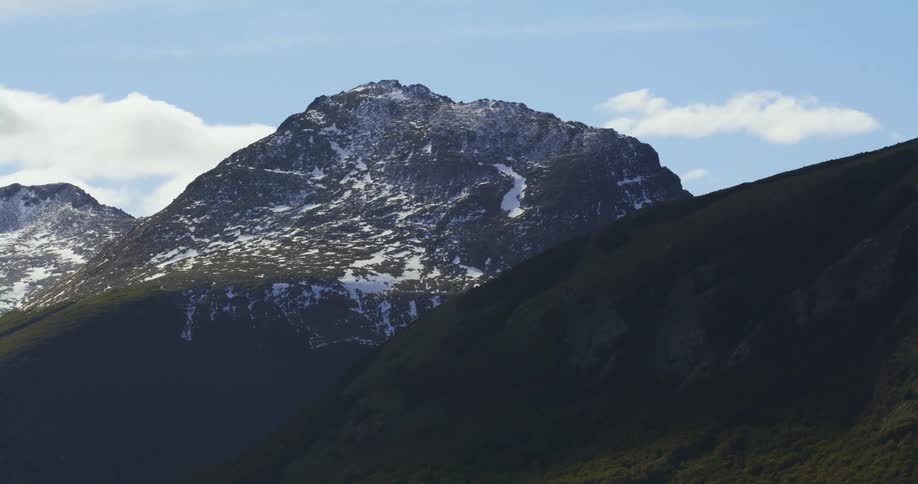 Patches of snow cover the side of a mountain