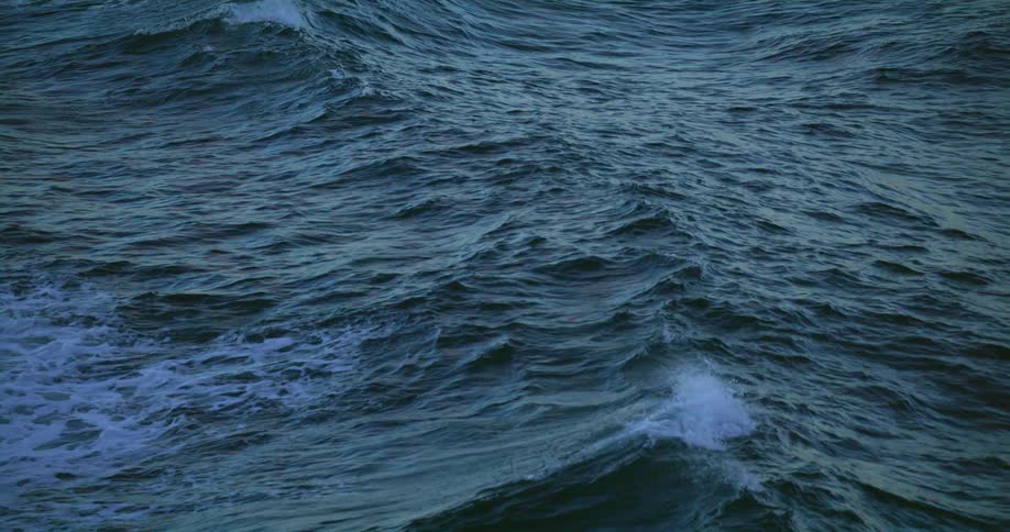 Waves roll across the surface of the ocean spraying foam