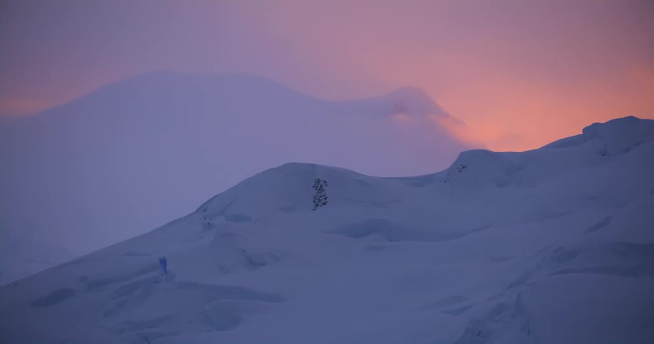 The sun glowing behind snow covered slopes