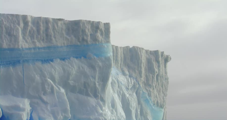An iceberg floats across the ocean on a snowy day