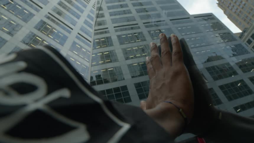 A woman puts her hand on a window so it looks like it is on the office building outside