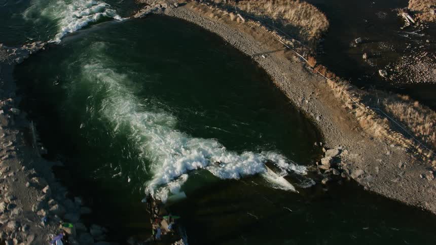 A group of people stand on rocks and wait to surf