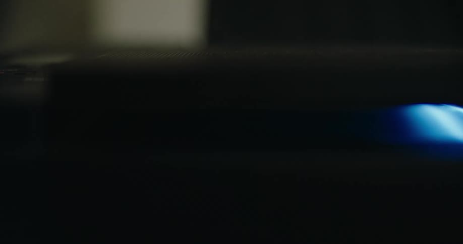 A light blue light moves across a dark object
