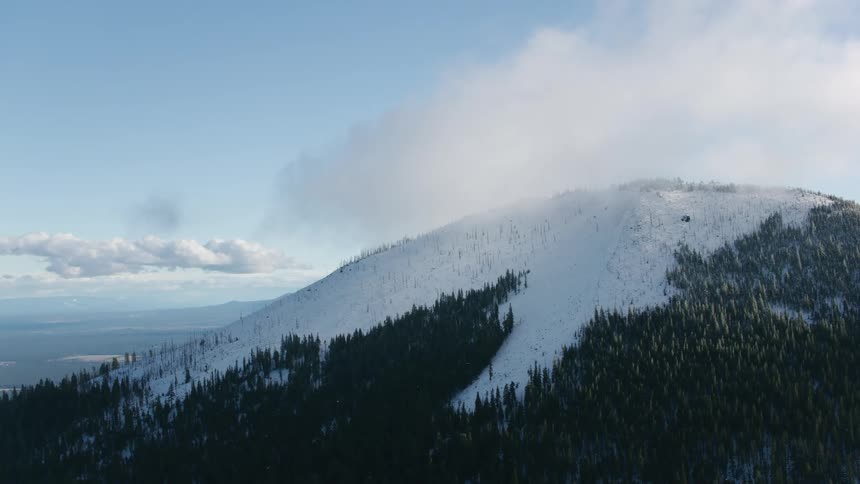 Fog moves over a snow capped mountain