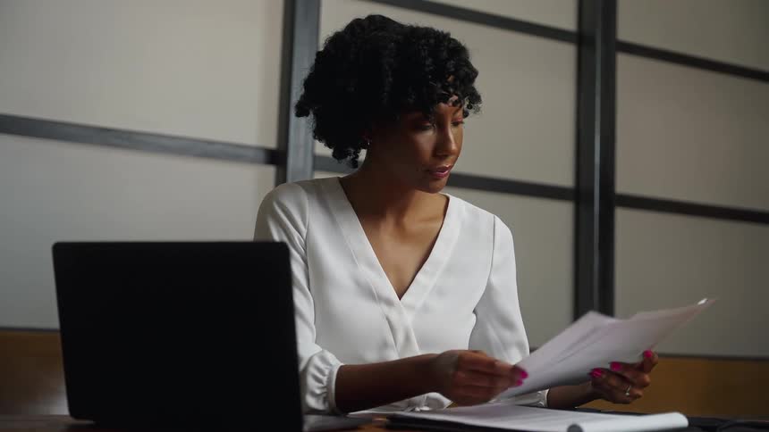 A woman sighs deeply as she sorts through pieces of paper in the conference room
