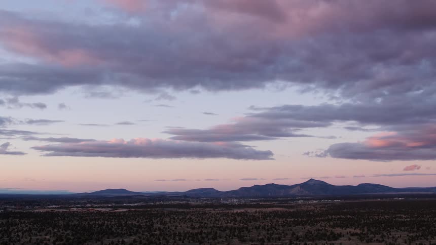A dusting of snow is visible in the brush with mountains on the horizon at sunrise
