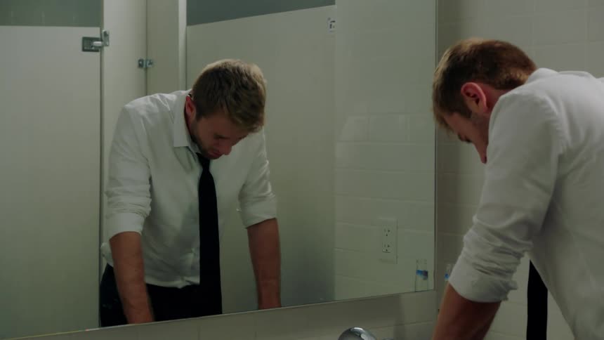 A man looking sad into a mirror in the bathroom