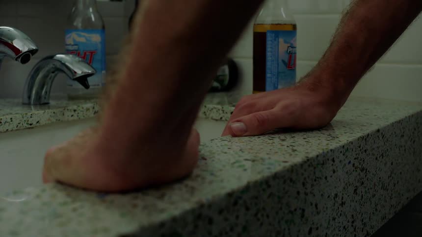 A man grabbing a sink in a bathroom
