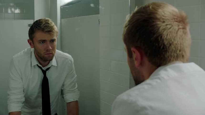 A man is looking into the bathroom mirror