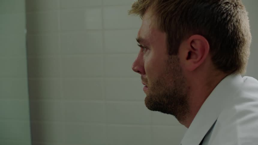 A man is in a public bathroom and he is talking to himself