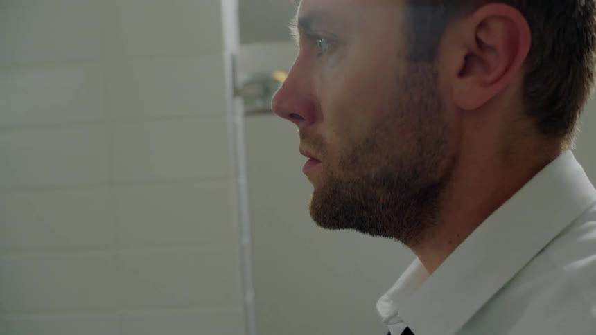 A man adjusts his tie in the bathroom