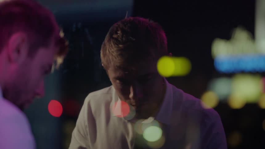 A man is looking at his reflection outdoors during the night time