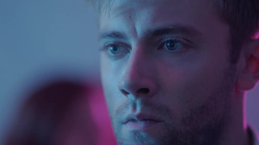Close up view of a man in a room with people is displayed