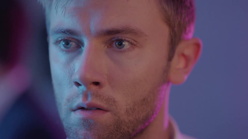 A man is in a room looking around and there are other people moving behind him