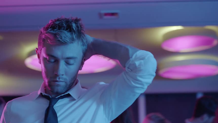 A man brushes his hair back at a party