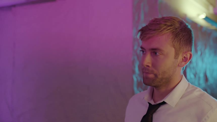 Man sighs and shakes his head under colored lighting