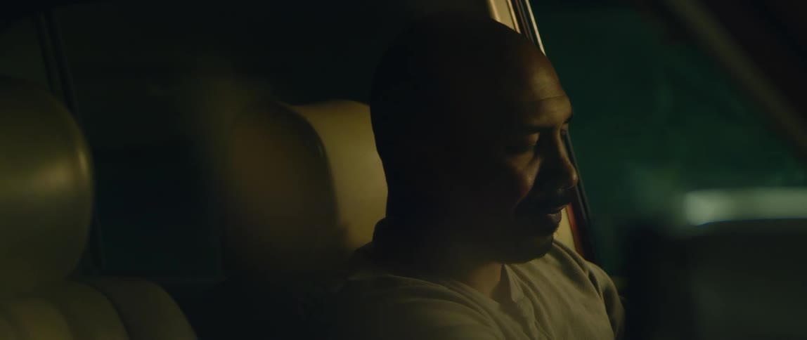 A man sits in his car at night and nods his head an then leans his head back on the seat rest