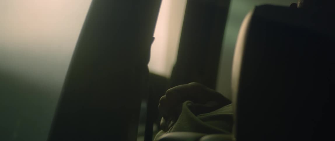 The back of a man as he sits in his car and rubs his shoulder