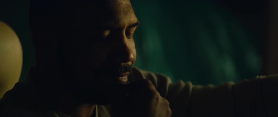 Bald bearded man sitting on the driver seat of a car parked inside a dimly lit garage
