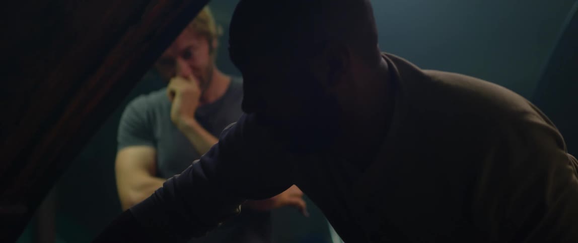 Two men talk while working on a car